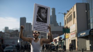 LOS ANGELES, CA - OCTOBER 22: Nick Keen participates in the ''National Day of Protest to Stop Police Brutality, Repression and the Criminalization of a Generation'' in the Skid Row area October 22, 2015 in Los Angeles, California. Keen holds a poster showing Michael Brown, who was killed by Ferguson police in 2014. Activists are marching in Los Angeles, New York City and some 30 other cities today to protest alleged police brutality.
