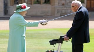 Britain's Queen Elizabeth II uses the sword that belonged to her father, George VI, as she confers the Honour of Knighthood on 100-year-old WWII veteran Captain Tom Moore at Windsor Castle in Windsor, west of London, on July 17, 2020.