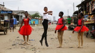 Ballet student Anthony Mmesoma Madu, center, dances in the street as fellow dancers look on in Lagos, Nigeria on Aug. 18, 2020