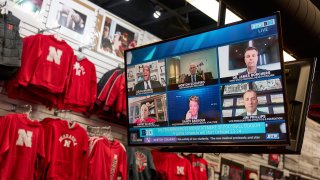 The Husker Hounds sports apparel store in Omaha, Neb., shows on television screens Wednesday, Sept. 16, 2020, a Big Ten virtual news conference to discuss the reopening of the football season. President Donald Trump was quick to spike the ball in celebration when the Big Ten announced the return of fall football at colleges clustered in some of the Midwest battleground states critical to his reelection effort.