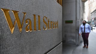 A man walks near the New York Stock Exchange (NYSE) on August 31, 2020 at Wall Street in New York City. - Wall Street stocks paused near record levels early Monday ahead of key economic data later in the week, with a newly-tweaked Dow index edging lower. The final session of a heady August opened on a lackluster note as markets await employment data and updates on the manufacturing and services sectors in the coming days. About 15 minutes into trading, the Dow Jones Industrial Average was down 0.4 percent to 28,539.83.