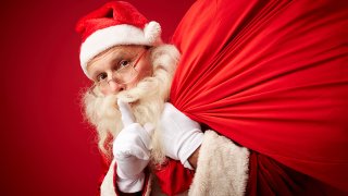 Santa with a finger over his mouth to hush