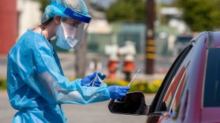 a Physician Assistant with AltaMed Health Services prepares to test a drive-through patient for COVID-19.