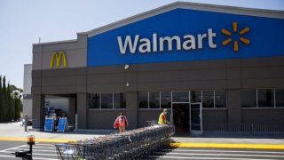In this July 16, 2020, file photo, an employee wearing a protective mask pulls carts towards a Walmart store in Lakewood, California.