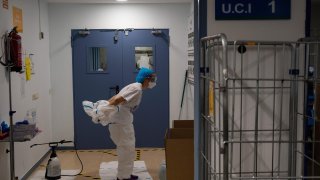 A healthcare worker takes off her protective suit after attending to coronavirus patients at the Intensive Care Unit (ICU) of the Severo Ochoa University Hospital in Leganes on October 16, 2020.