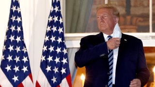 U.S. President Donald Trump removes his mask upon return to the White House from Walter Reed National Military Medical Center on October 05, 2020 in Washington, DC. Trump spent three days hospitalized for coronavirus.