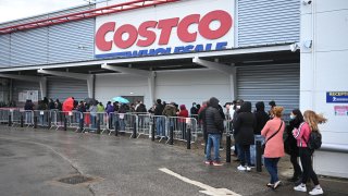 Shoppers wait outside a Costco wholesale store in Leeds, northern England