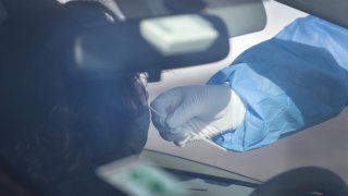 A worker tests a resident at a drive-up COVID-19 test site on November 13, 2020 in Aurora, Illinois.