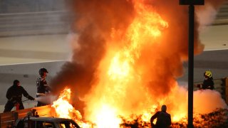 Staff extinguish flames from Haas driver Romain Grosjean of France's car after a crash during the Formula One race in Bahrain International Circuit in Sakhir, Bahrain, Sunday, Nov. 29, 2020.