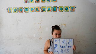 Gabriela Fajardo, a 26-year-old Honduran seeking asylum in the United States, teaches a Zoom class for Central American children living in camps, various shelters and apartments in other parts of Mexico, Nov. 20, 2020, from a hallway of a building in Matamoros, Mexico.
