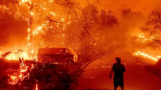 Bruce McDougal watches embers fly over his property as the Bond Fire burns through the Silverado community in Orange County, Calif., Dec. 3, 2020.