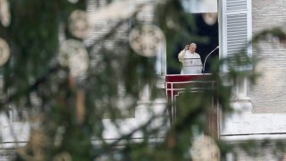 Pope Francis, framed by a Christmas tree, waves as he arrives to recite the Angelus noon prayer from the window of his studio overlooking St.Peter's Square, at the Vatican, Dec. 6, 2020.