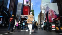 A man wearing a hazmat suit and a mask walks down an emptied Times Square on March 14, 2020 in New York City.