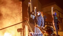 Protesters raise their fists as flames rise behind them in front of the Third Police Precinct on May 28, 2020, in Minneapolis, Minnesota, during a protest over the death of George Floyd.