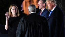 Supreme Court Associate Justice Clarence Thomas swears in Amy Coney Barrett as a U.S. Supreme Court Associate Justice, flanked by her husband Jesse M. Barrett, during a ceremony on the South Lawn of the White House, Oct. 26, 2020, in Washington, D.C.