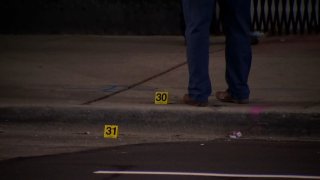 A Chicago police officer stands next to evidence markers outside of a shooting scene in the city's Burnside neighborhood on Dec. 19, 2020