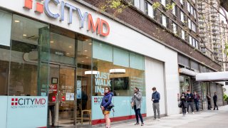 People wearing masks wait in line outside a CityMD location to be tested for coronavirus on April 30, 2020 in New York City, United States.