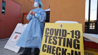 Hands of a laboratory worker holding positive test tube for COVID-19 coronavirus