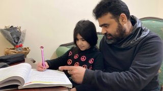 Syrian refugee Mahmoud Mansour, 47, helps his youngest daughter Sahar, 8, with her homework at his rented apartment in Amman, Jordan, Wednesday, Jan. 20, 2021. President Joe Biden has vowed to restore America's place as a world leader in offering sanctuary to the oppressed by raising the cap on the number of refugees allowed in each year. Mansour's family had completed the work to go to the United States when the Trump administration issued its travel ban barring people from Syria indefinitely and suspending the refugee program for 120 days.