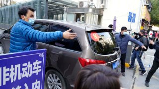 A car that's part of a convoy carrying the World Health Organization team of researchers arrives at the Hubei Provincial Hospital