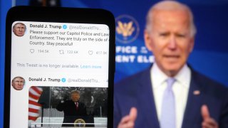In this photo illustration, Donald Trump Twitter messages are seen displayed on a smartphone screen in front of a fragment of a video with U.S. President-elect Joe Biden addressing Trump supporters as they continue with protests in and near the U.S. Capitol in Washington during the U.S. Congress session to certify the 2020 Presidential election results.