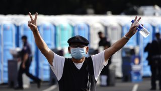 A person wearing a protective mask gestures after receiving a dose of Covid-19 vaccine.