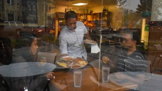 Michael Demissie, C, serves Tevi'a Johnson, L, and Tivon Johnson at Zenebech Restaurant in Washington, DC.