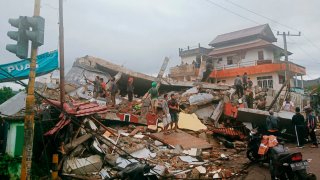 Residents inspect earthquake-damaged buildings in Mamuju, West Sulawesi, Indonesia, Friday, Jan. 15, 2021. A strong inland and shallow earthquake hit eastern Indonesia early Friday causing people to panic in parts of the country's Sulawesi island and run to higher ground.