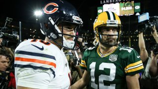 Bears quarterback Mitchell Trubisky, wearing a white jersey and the team's signature navy blue helmet, greets Packers quarterback Aaron Rodgers, who is wearing the Packers' gold helmet and a green jersey, after a 2019 game at Lambeau Field