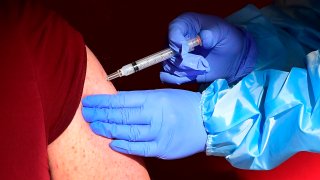 A senior citizen receives a COVID-19 vaccine at the Corona High School gymnasium in the Riverside County city of Corona, California on January 15, 2021, a day after California began offering the coronavirus vaccine to residents 65 and older.