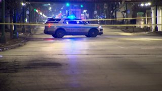 A Chicago police car sits parked on a street in Englewood, with crime scene tape in the foreground