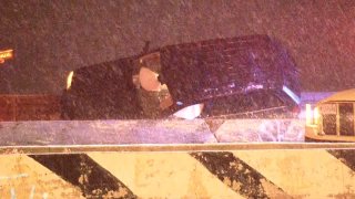 A black SUV, with air bags deployed, is shown behind a concrete barrier on Lake Shore Drive, with snow falling in the foreground