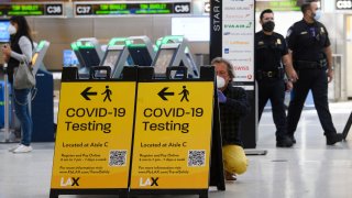 In this Feb. 4, 2021, file photo, a traveler takes a photo of a COVID-19 testing sign at the Tom Bradley International Terminal (TBIT) amidst travel restrictions during the COVID-19 pandemic at Los Angeles International Airport (LAX) in Los Angeles, California.