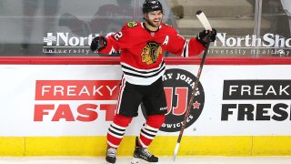 Blackhawks forward Alex DeBrincat, wearing a red jersey with an "A" on the left shoulder, celebrates after scoring a game winning goal against Columbus