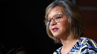 Illinois Representative Robin Kelly is pictured addressing Congress while wearing a blue and white dress, along with glasses