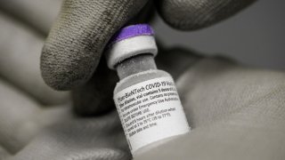 A pharmacist holds with gloved hands a vial of the undiluted Pfizer-BioNTech vaccine for Covid-19