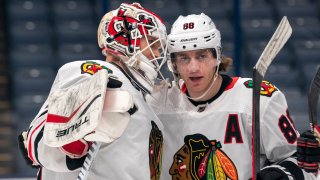 Kevin Lankinen and Patrick Kane, both wearing white Blackhawks jerseys, congratulate one another on a win over the Blue Jackets