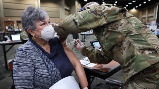 TINLEY PARK, ILLINOIS – JANUARY 26: SSgt Alana Veach of the Illinois Air National Guard administers a COVID-19 vaccine to Marcy Greune at a mass vaccination center established at the Tinley Park Convention Center on January 26, 2021 in Tinley Park, Illinois. The site is the first large-scale vaccination center in Cook County, which includes the city of Chicago.  Workers at the site will be able to distribute 3000 vaccinations-per-day once adequate vaccine supplies become available.  (Photo by Scott Olson/Getty Images)