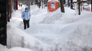 A pedestrian navigates a snow-covered sidewalk on February 16, 2021 in Chicago