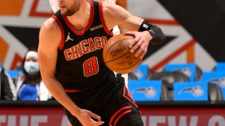 Zach LaVine, wearing a black and red Bulls jersey, dribbles a ball against the Orlando Magic