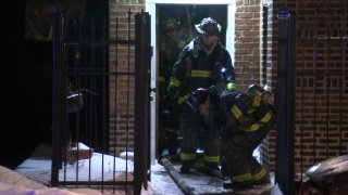 Chicago firefighters, dressed in black and yellow uniforms, walk out of a building as they fight a blaze on Feb. 14 in the city's Oakland neighborhood