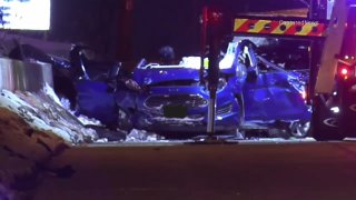 A blue Ford Fiesta, with the roof torn off and airbags deployed, sits at the scene of a fatal crash that left four people dead