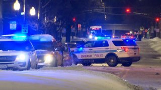 Chicago police cars are parked on a street, with lights on, as they investigate a shooting on the city's South Side