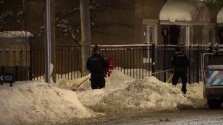 Chicago police officers stand in a snow drift, holding red crime scene tape at the scene of a fatal shooting in Bridgeport