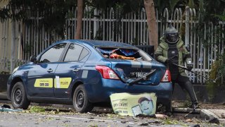 An Indonesian anti-bomb unit (C) collects evidences after a bomb exploded in Makassar on March 28, 2021.