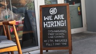 In this March 5, 2021, file photo, a "we are hiring sign" in front of the Buya restaurant in Miami, Florida. The restaurant is looking to hire more workers as the U.S. unemployment rate drops to 6.2 percent, as many restaurants and bars reopen. Officials credit the job growth to declining new COVID-19 cases and broadening vaccine immunization that has helped more businesses reopen with greater capacity.