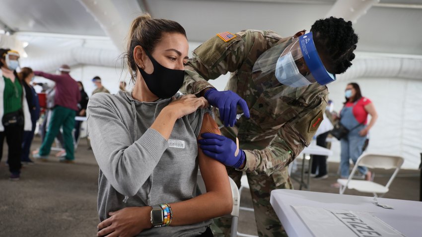 In this March 9, 2021, file photo, a U.S. Army soldier from the 2nd Armored Brigade Combat Team, 1st Infantry Division, immunizes Mariana Nascimento with the Pfizer COVID-19 vaccine at the Miami Dade College North Campus in North Miami, Florida.