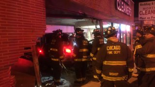 Chicago firefighters stand around a black SUV that had crashed into a building in the city's Portage Park neighborhood