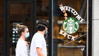 People wear protective face masks outside Starbucks in midtown as the city moves into Phase 2 of re-opening following restrictions imposed to curb the coronavirus pandemic on June 23, 2020 in New York City.