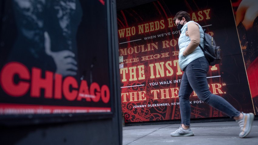 NEW YORK, NEW YORK – OCTOBER 13: A person wearing a mask walks past posters for Chicago and Moulin Rouge in Times Square on October 13, 2020 in New York City. The pandemic has caused long-term repercussions throughout the tourism and entertainment industries, causing short-term and permanent closures of historic and iconic venues while keeping the doors of Broadway suspended until June of 2021 costing the city and businesses billions in revenue. (Photo by Alexi Rosenfeld/Getty Images)